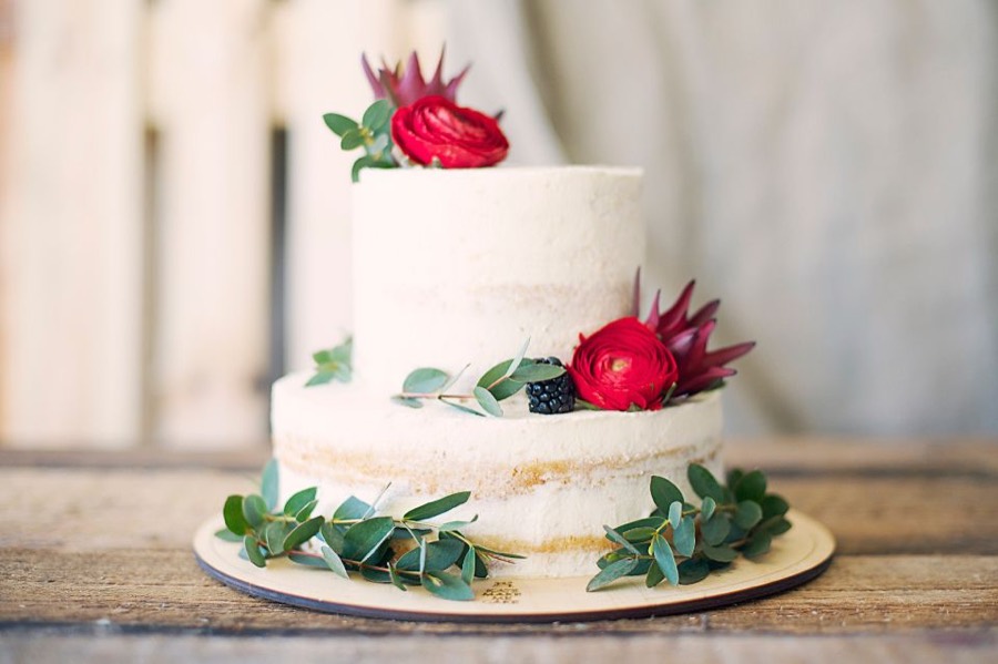 A white layered cake with red flowers